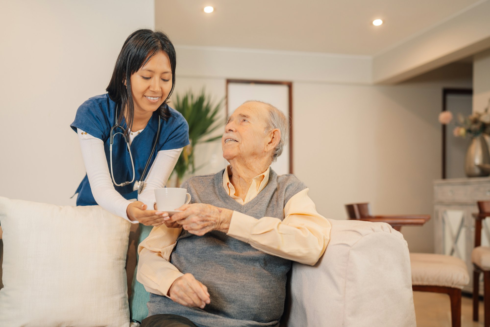 Home caregiver serving coffee to an elder man